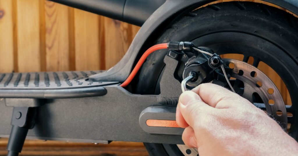 Monteur repariert Bremsanlage eines Elektro-Scooters